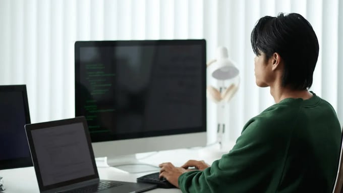 Programador trabajando con múltiples monitores y laptops, expuesto a los costos ocultos de la fragmentación tecnológica.