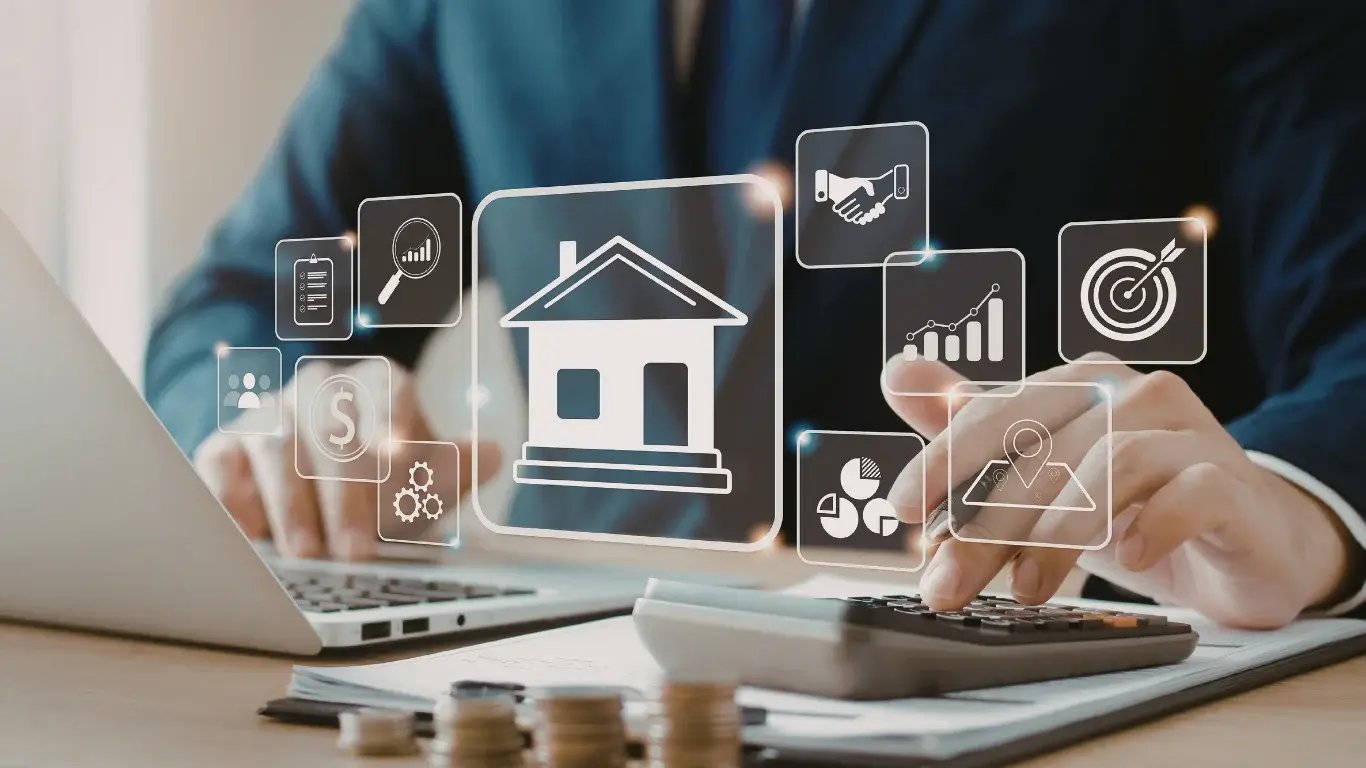 Broker usa calculadora y laptop con iconos digitales flotantes de analítica, ventas y viviendas de un CRM inmobiliario.