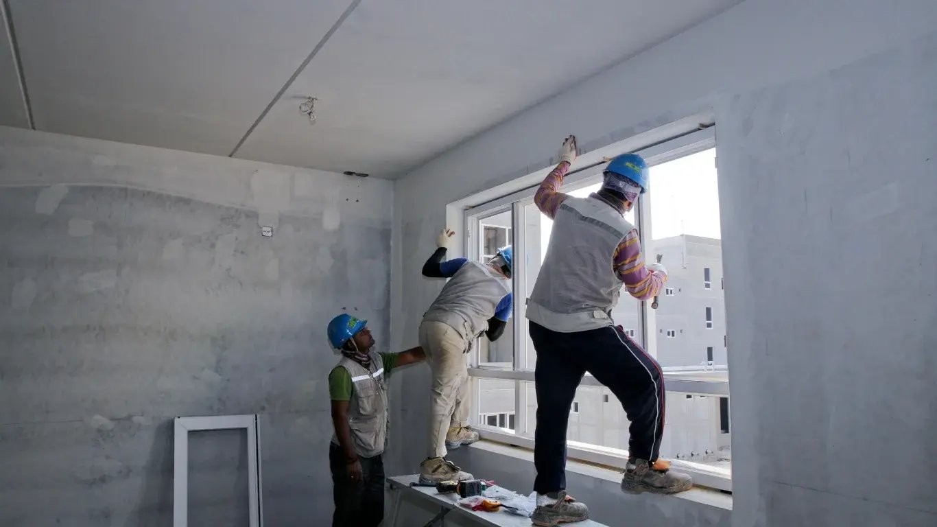 Obreros instalando marcos de ventanas en obra, un proceso clave revisado por el supervisor de postventa inmobiliaria.